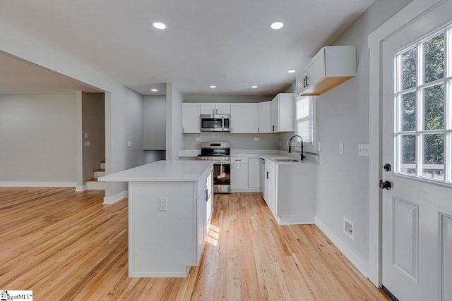 kitchen featuring a center island, white cabinets, stainless steel appliances, and sink