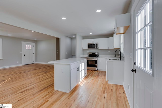 kitchen featuring sink, light wood-type flooring, a kitchen island, stainless steel appliances, and white cabinets