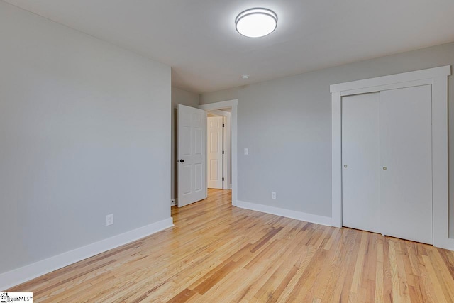 unfurnished bedroom with a closet and light wood-type flooring