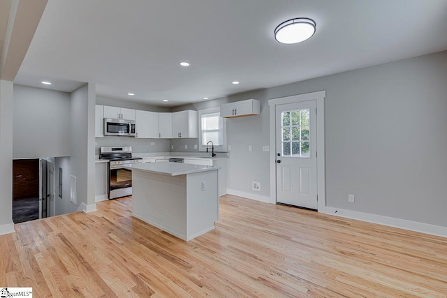 kitchen featuring sink, a center island, white cabinetry, appliances with stainless steel finishes, and light hardwood / wood-style floors