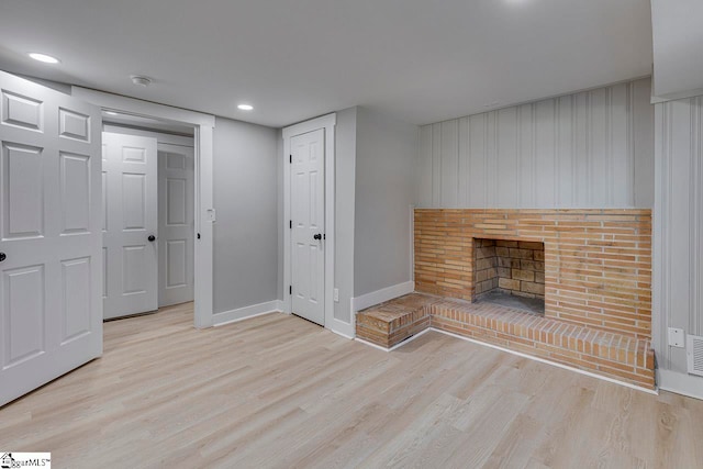 unfurnished living room with a brick fireplace and light hardwood / wood-style floors