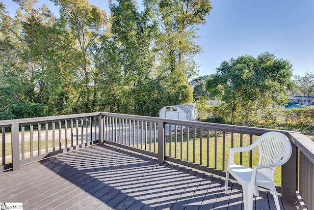 wooden deck featuring a yard and a storage unit