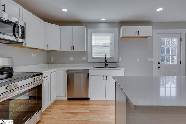 kitchen featuring appliances with stainless steel finishes, white cabinetry, sink, and a wealth of natural light