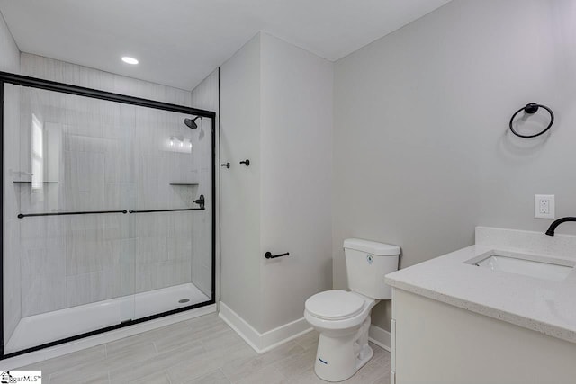 bathroom featuring vanity, a shower with shower door, and toilet