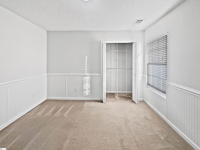 unfurnished bedroom with light carpet, a closet, and a textured ceiling