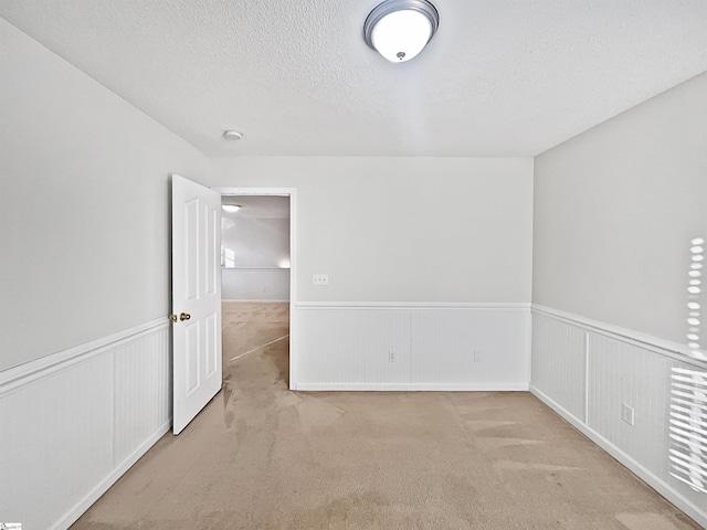 unfurnished room with light carpet and a textured ceiling