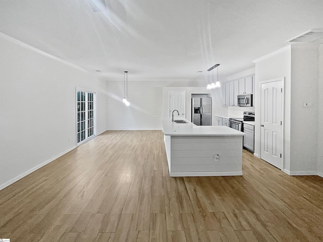 kitchen featuring light wood-type flooring, stainless steel appliances, pendant lighting, crown molding, and a center island with sink