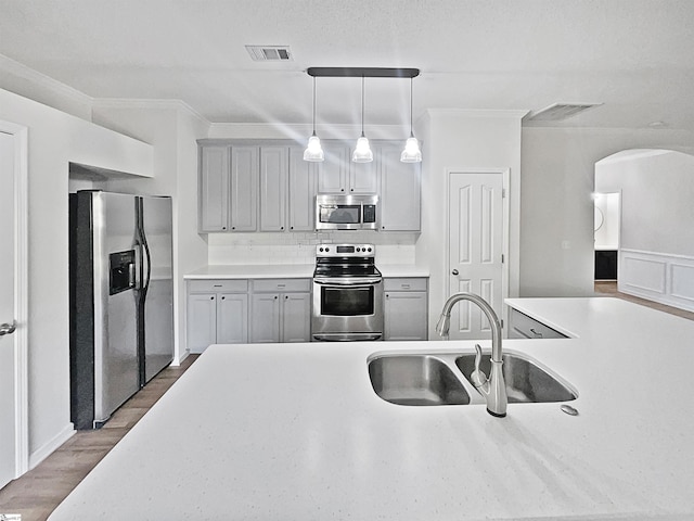 kitchen with hardwood / wood-style flooring, hanging light fixtures, sink, gray cabinets, and appliances with stainless steel finishes