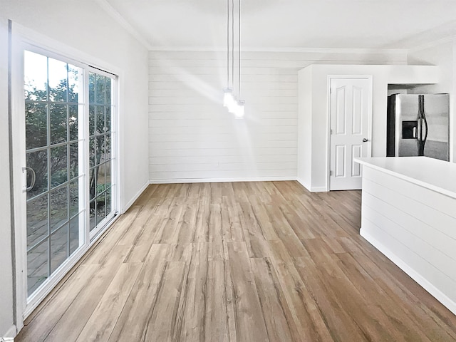 interior space featuring crown molding, wooden walls, and light wood-type flooring