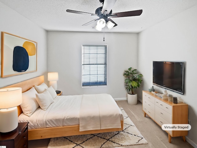 bedroom with a textured ceiling, light colored carpet, and ceiling fan