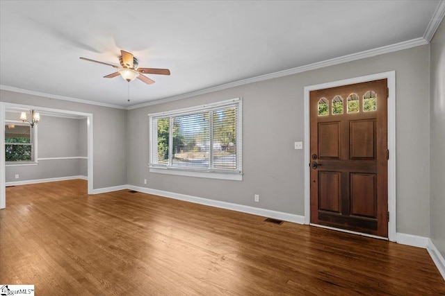 entrance foyer with ceiling fan with notable chandelier, a wealth of natural light, ornamental molding, and dark hardwood / wood-style floors