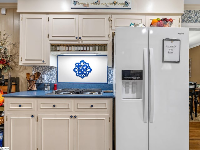 kitchen with stainless steel gas cooktop, wood-type flooring, white refrigerator with ice dispenser, and backsplash