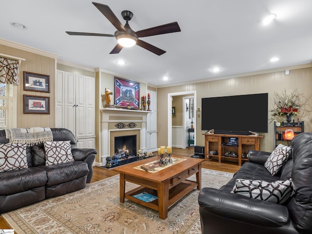 living room with ornamental molding, built in shelves, light wood-type flooring, and ceiling fan