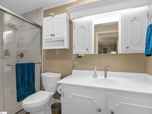 bathroom with toilet, ornamental molding, vanity, and a shower with door