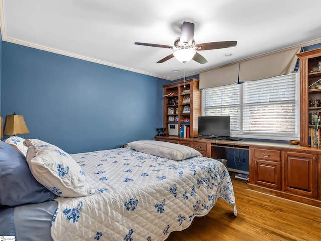 bedroom with light hardwood / wood-style floors, ornamental molding, built in desk, and ceiling fan