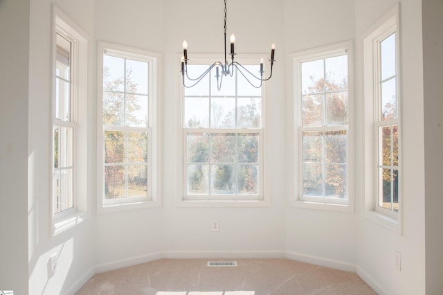 unfurnished dining area with a notable chandelier, carpet floors, and a healthy amount of sunlight