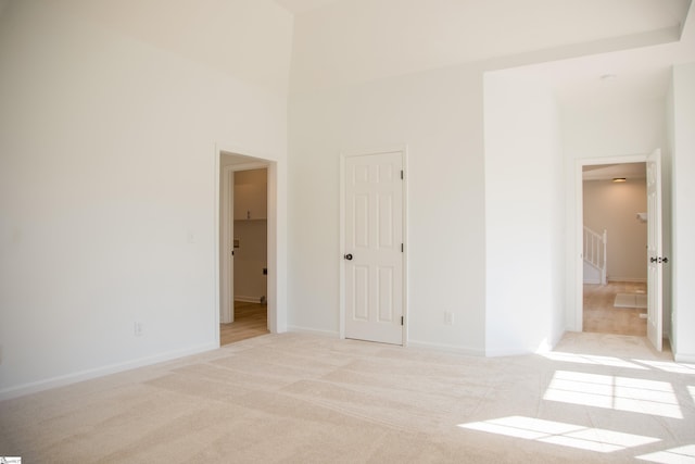 carpeted spare room featuring a towering ceiling