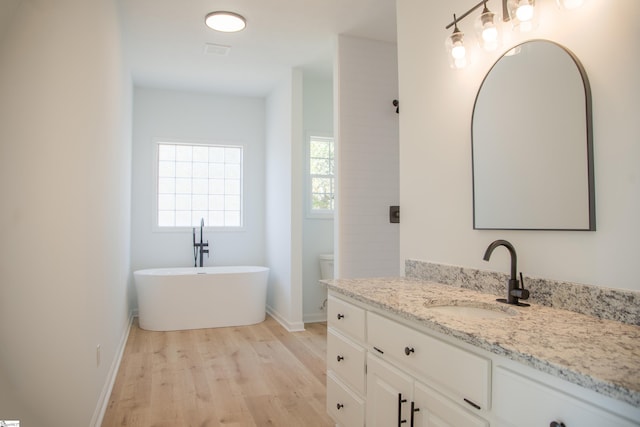 bathroom with vanity, a tub, toilet, and wood-type flooring