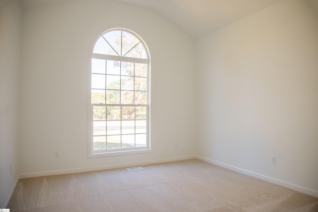 carpeted spare room featuring lofted ceiling