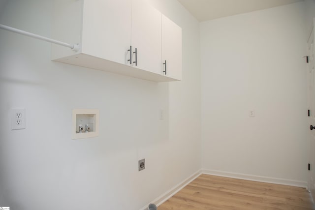 laundry room with hookup for a washing machine, light hardwood / wood-style flooring, electric dryer hookup, and cabinets