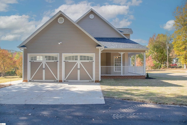 view of front of property featuring a porch, a front lawn, and a garage