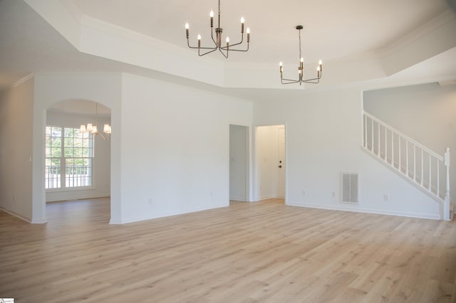 unfurnished living room featuring crown molding, a tray ceiling, and light hardwood / wood-style flooring