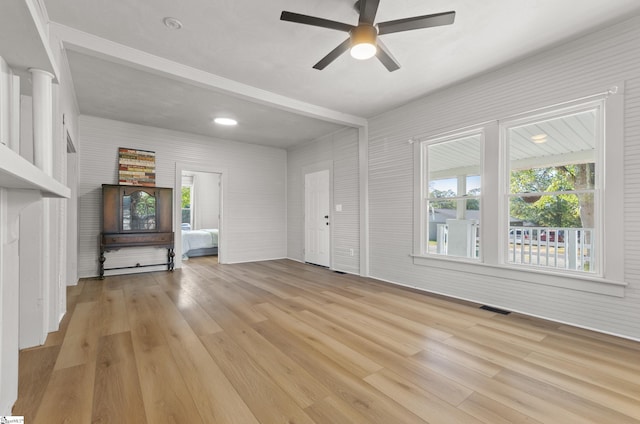 unfurnished living room with ornate columns, light wood-type flooring, and ceiling fan