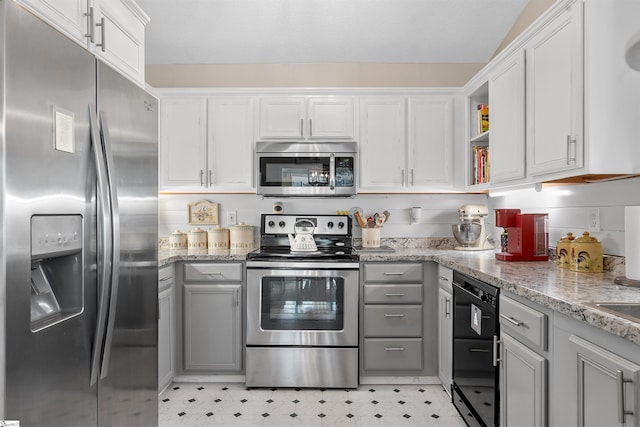 kitchen featuring gray cabinetry, light stone countertops, stainless steel appliances, and white cabinetry