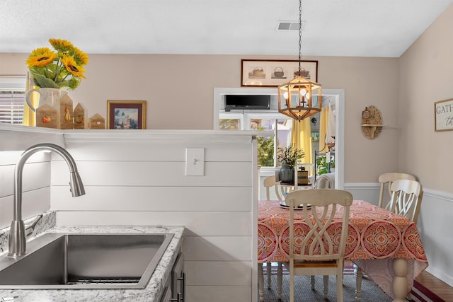 kitchen featuring hardwood / wood-style flooring, hanging light fixtures, sink, a chandelier, and white cabinets