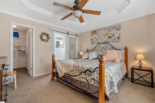 bedroom with a barn door, a tray ceiling, light colored carpet, and ceiling fan