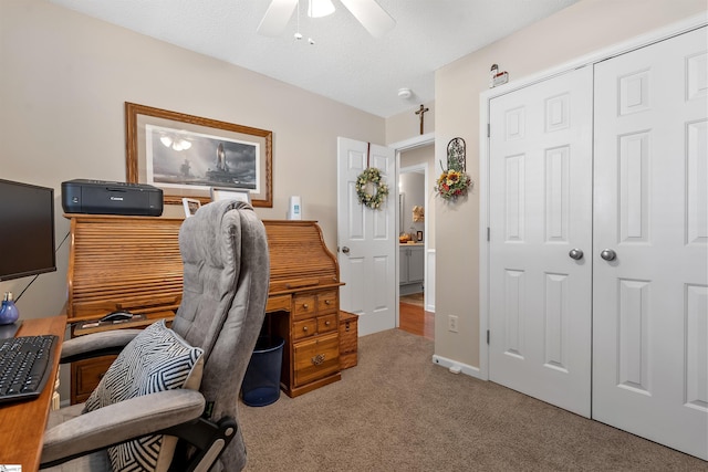 office featuring ceiling fan, a textured ceiling, and light colored carpet