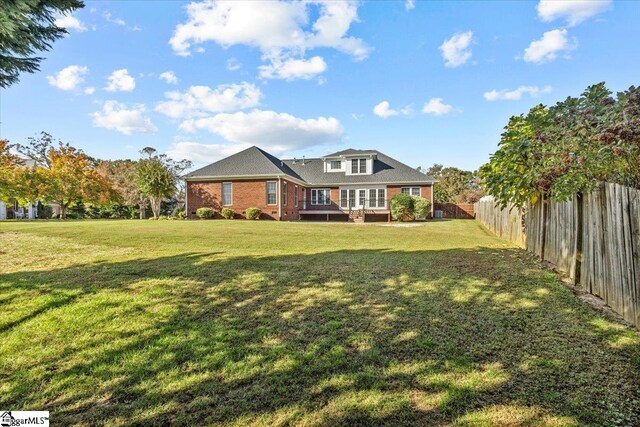 back of house featuring a wooden deck and a lawn