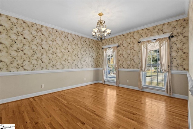 empty room with light hardwood / wood-style floors, crown molding, and a chandelier