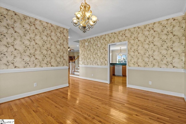 empty room featuring crown molding, hardwood / wood-style flooring, and a chandelier