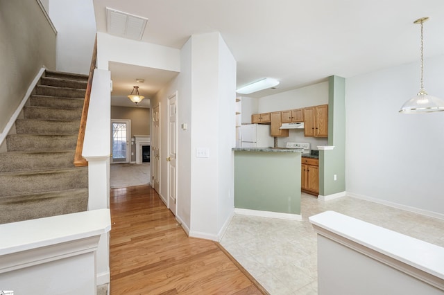 interior space featuring white fridge, decorative light fixtures, and light wood-type flooring