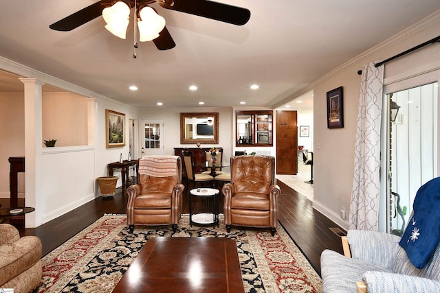 living room featuring crown molding, dark wood-type flooring, ornate columns, and ceiling fan