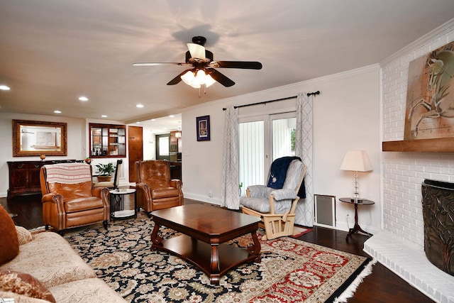 living room with crown molding, a brick fireplace, dark hardwood / wood-style floors, and ceiling fan