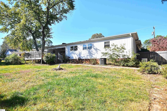 view of front facade featuring a front yard, central AC, and a wooden deck