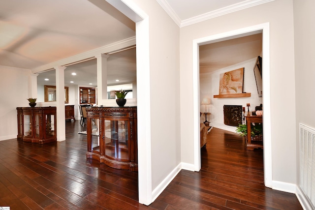 corridor featuring decorative columns, ornamental molding, and dark hardwood / wood-style flooring