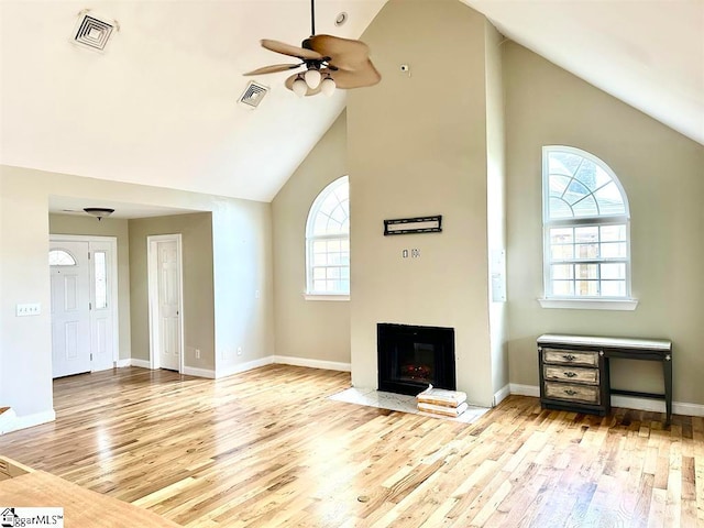 unfurnished living room featuring high vaulted ceiling, light wood-type flooring, and ceiling fan