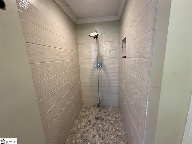 bathroom featuring ornamental molding, a shower, and tile walls