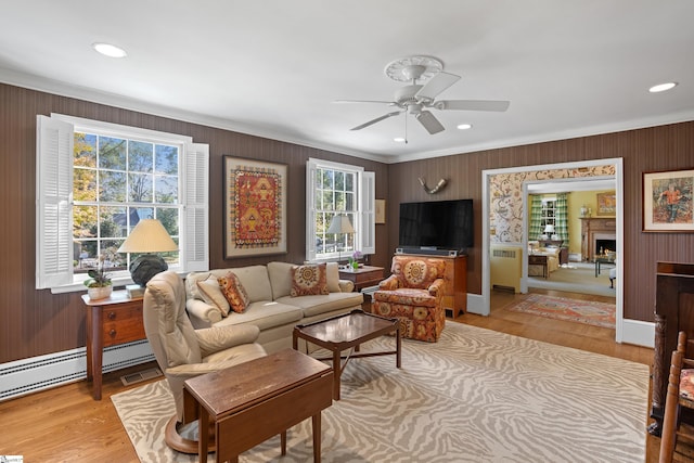 living room featuring ornamental molding, light hardwood / wood-style flooring, a healthy amount of sunlight, and ceiling fan