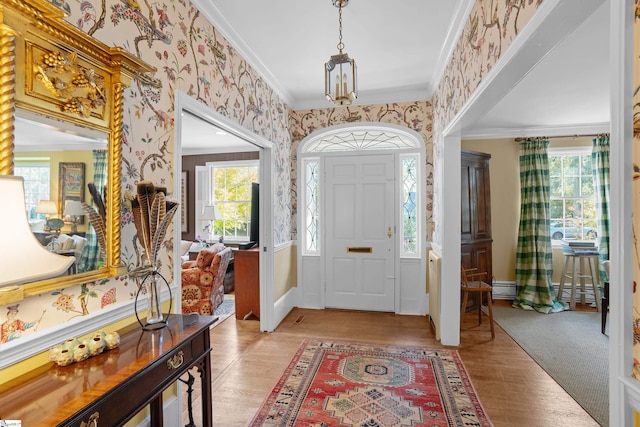 entryway featuring a wealth of natural light, crown molding, and light hardwood / wood-style floors