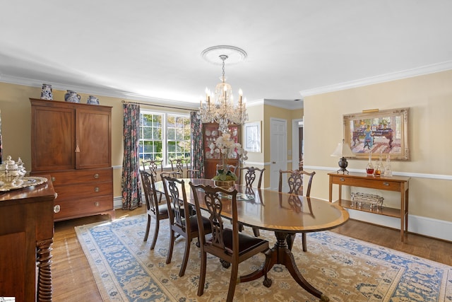 dining space with ornamental molding, a chandelier, and light wood-type flooring