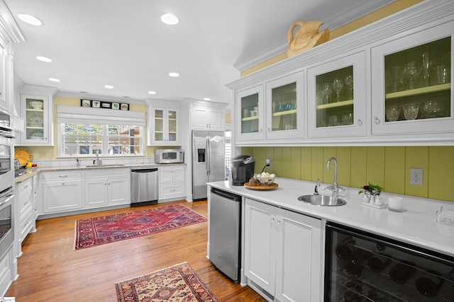 kitchen featuring light hardwood / wood-style flooring, wine cooler, sink, white cabinets, and appliances with stainless steel finishes