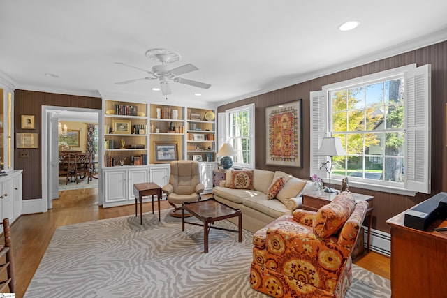 living room with light hardwood / wood-style flooring, wood walls, a wealth of natural light, and baseboard heating