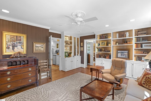 living area featuring ornamental molding, light hardwood / wood-style flooring, and ceiling fan