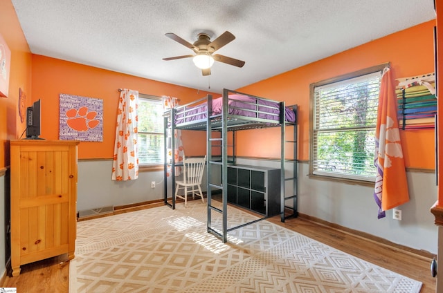 bedroom featuring a textured ceiling, multiple windows, and hardwood / wood-style floors