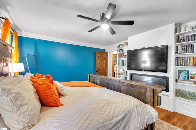 bedroom with ornamental molding, a textured ceiling, light wood-type flooring, and ceiling fan