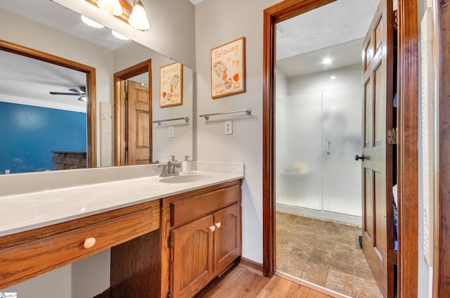 bathroom with ceiling fan, an enclosed shower, hardwood / wood-style flooring, vanity, and crown molding